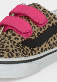 Chaussure enfant à imprimé léopard avec bande latérale noire, brides velcro roses et semelle blanche sur fond clair.