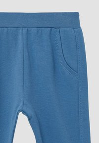 Blauwe joggingbroek met een elastische tailleband, voorzien van een zijzak en zachte, textuurachtige stof. Stiksels zijn zichtbaar langs de randen.