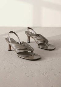 Grey leather slingback high-heeled sandals with twisted front straps and square toes, featuring a low block heel and textured surface.