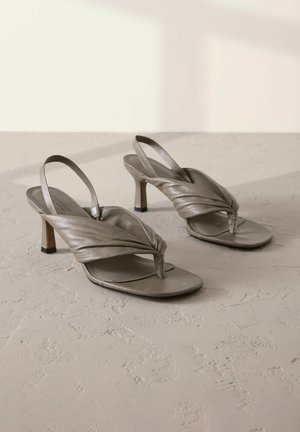 Pilkos odinės slingback aukštakulnės šlepetės su suktais priekiniais dirželiais ir kvadratiniais pirštais, su žemu blokuotu kulnu ir tekstūruota paviršiumi.