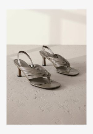 Szürke bőrből készült, pántos, magassarkú szandál, csavart elülső pántokkal és négyzetes orral, alacsony blokk sarka és texturált felülete van.