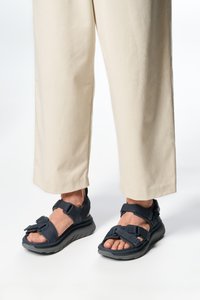 Námořnické sandály s nastavitelnými popruhy, gumovou podešví a texturovanou stélkou; nošeny s krémovými širokými kalhotami.