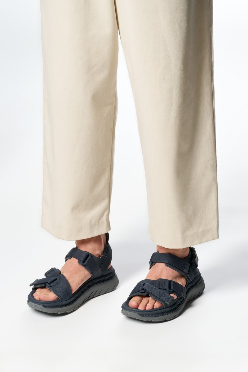 Námořnické sandály s nastavitelnými popruhy, gumovou podešví a texturovanou stélkou; nošeny s krémovými širokými kalhotami.