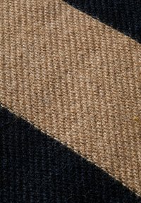 Gros plan de tissu tissé avec des rayures diagonales beige et noires montrant des fibres et des fils texturés.