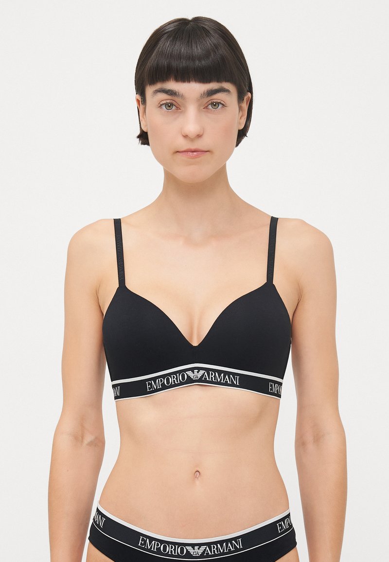Zwarte draadloze beha met een diepe decolleté, verstelbare banden en een elastische band met logo-detail. Rekbare katoenmix.