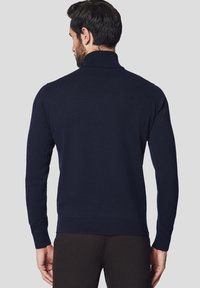Granatowy sweter z dzianiny z wysokim kołnierzem, dopasowany krój, ściągacze przy mankietach i u dołu, prezentujący gładką teksturę i minimalistyczny styl.