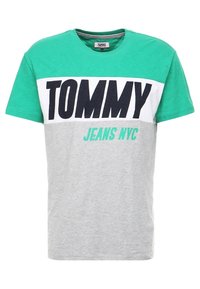 Camiseta de manga corta con un diseño de bloques de color verde, blanco y gris. Presenta un texto en negrita de color negro que dice "TOMMY" y "JEANS NYC" en color turquesa. Material de algodón.