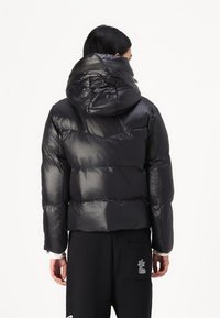 Black puffer jacket with a hood, featuring glossy finish and structured quilted design. Elastic cuffs and relaxed fit enhance comfort.