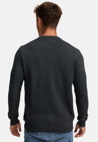 Ciemnoszary sweter z fakturowanym wzorem jodełki, ściągaczem przy kołnierzu i mankietach oraz klasycznym krojem. Widok od tyłu.