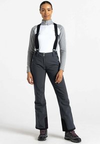 Schwarze wasserdichte Skihosen mit verstellbaren Trägern, zwei seitlichen Reißverschlusstaschen und einer lockeren Passform. Kombiniert mit einem grauen Langarmoberteil.