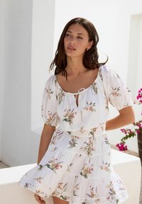 Witte jurk met bloemenprint, een vierkante halslijn, korte pofmouwen en een tiered rok. Zachte plooien en een gerimpelde zoom.