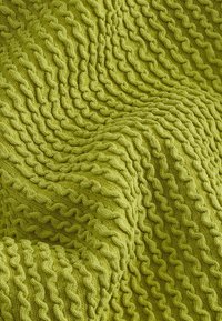 Couverture en tricot d'un vert lime vibrant, présentant un motif texturé en vagues avec des points surélevés, créant de la profondeur et un intérêt visuel.