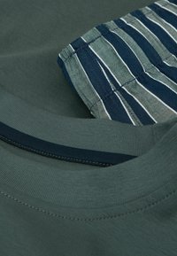 Krátký rukáv zelené tričko s námořnickým límcem a pruhovaným vzorem, s hladkým povrchem a kontrastním prošitím.