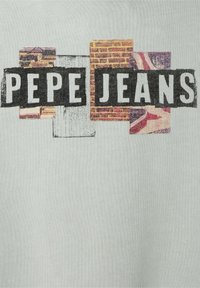 Sivá tkanina s textom "PEPE JEANS" v čiernej farbe na pozadí s farebným a textúrovaným vzorom.