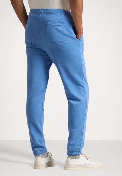 Pantaloni de trening bleu deschis, confecționați dintr-un material moale, cu talie elastică, buzunare laterale și un buzunar pe spate. Design cu picioare conice și manșete.