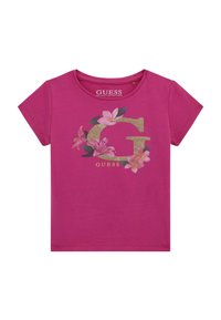 Fuksija bombažna majica s kratkimi rokavi, ki ima velik zlati logotip "G" okrašen s pisanim cvetličnim vzorcem in besedo "GUESS" spodaj. Okrogla ovratnica.