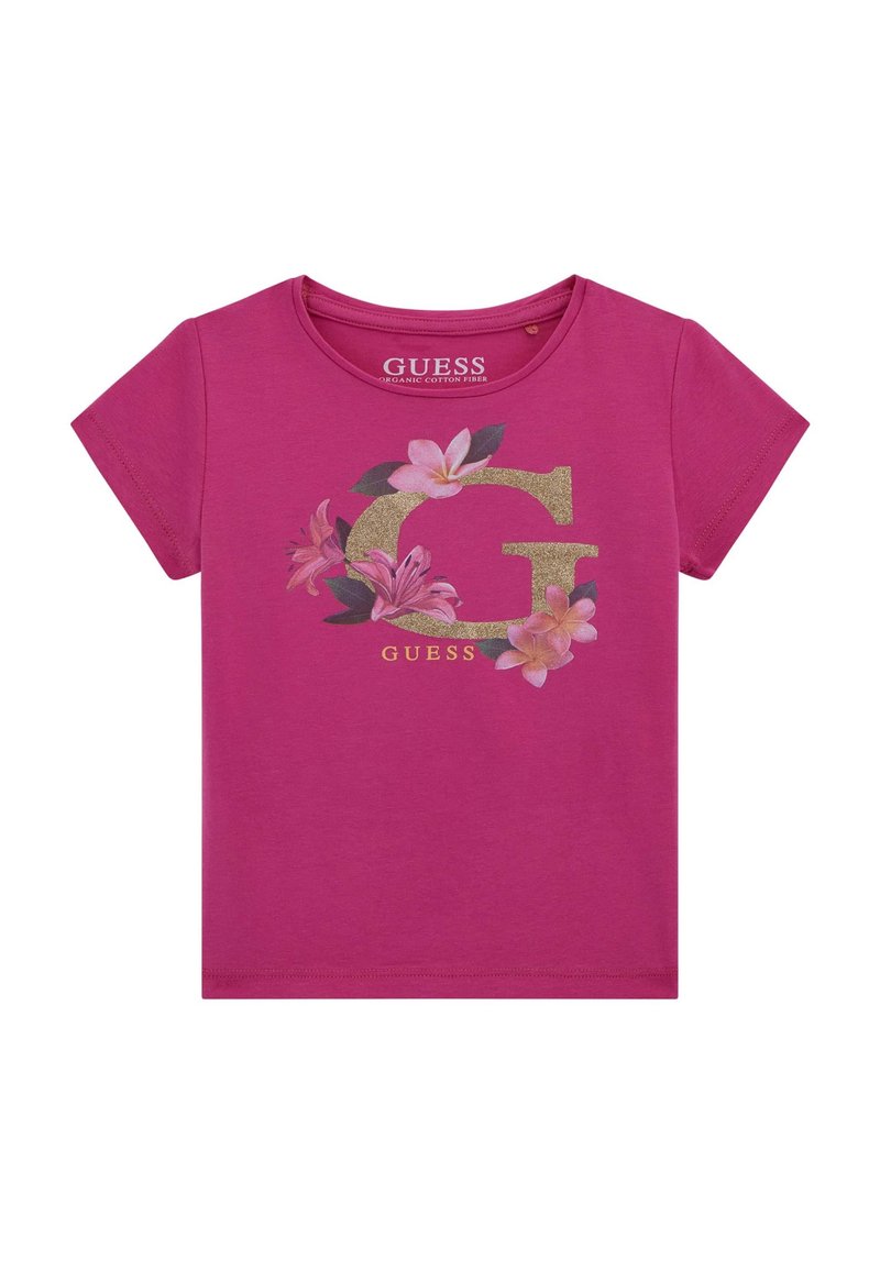 Fuksija bombažna majica s kratkimi rokavi, ki ima velik zlati logotip "G" okrašen s pisanim cvetličnim vzorcem in besedo "GUESS" spodaj. Okrogla ovratnica.