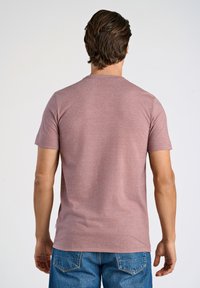 T-paita lyhyillä hihoilla, pyöreä pääntie ja ruusukvartsinen väri, valmistettu pehmeästä puuvillasekoitteesta, jossa on rento istuvuus ja minimaalinen brändäys helmassa.