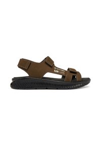 Brown suede sandal with wide adjustable straps, open toe, and a textured black rubber sole. Features branding on the side.