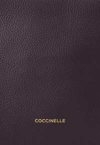 Portafoglio in pelle texturizzata viola con logo "Coccinelle" in rilievo oro nella parte inferiore. Finitura liscia e durevole con un aspetto a grana.