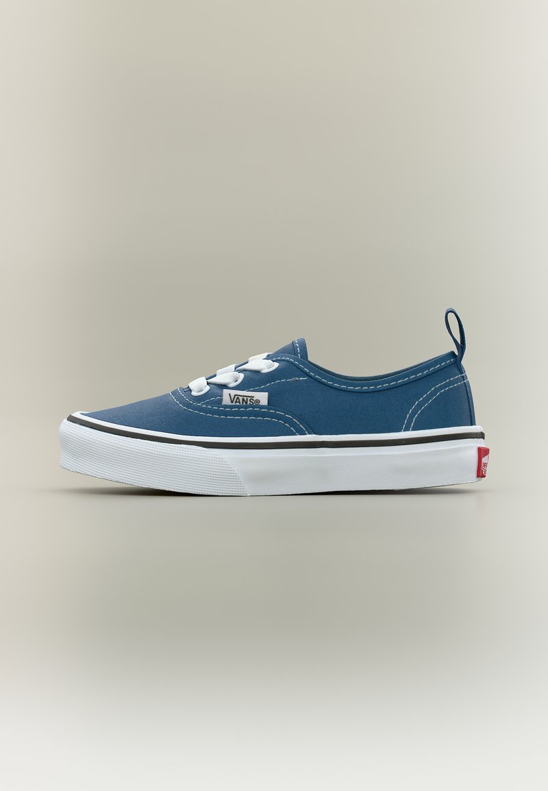 Μπλε παπούτσι Vans χαμηλού προφίλ με λευκά κορδόνια, λευκή καουτσούκ σόλα, μαύρη λεπτομέρεια γραμμής και κόκκινη ετικέτα λογότυπου στη φτέρνα πάνω σε απλό φόντο.