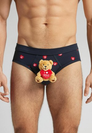Caleçons marins avec des motifs de cœurs rouges et le texte « Je t'aime », présentant un petit ours en peluche avec un cœur assorti sur le devant.
