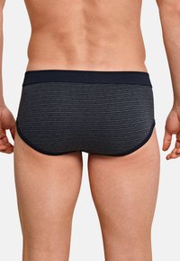 Marineblauwe zwemslips met horizontale strepen, elastische tailleband en een strakke pasvorm. De stof lijkt glad met een lichte glans.