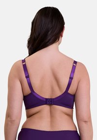 Soutien-gorge violet avec des bretelles réglables, fermeture à crochets et œillets, texture lisse et bords festonnés, montré de l'arrière.