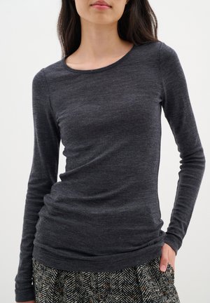 Long-sleeve gray top made of soft, stretchy fabric. Features a round neckline and fitted silhouette, paired with a patterned skirt.