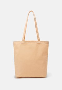 Sac cabas en coton beige avec deux longues anses, design simple, debout sur fond blanc.