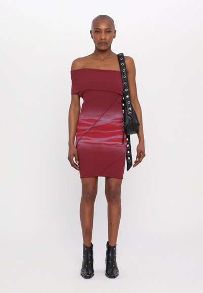 Abito maroon senza spalle con design a gradiente e linee diagonali. Abbinato a stivali neri con borchie fino alla caviglia e una piccola borsa nera.