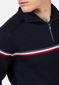 Maglione zip nella tonalità navy con lavorazione a maglia textured, caratterizzato da un colletto alto e righe orizzontali in rosso, bianco e blu sul petto.