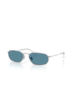 Lunettes de soleil à monture argentée avec verres polarisés bleus et branches fines reposant sur une surface blanche.