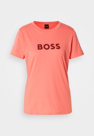 Korallinpinkki t-paita, jossa on paksuilla mustilla kirjaimilla "BOSS" painettuna edessä. Yksinkertainen pyöreä kaula-aukko ja lyhyet hihat.
