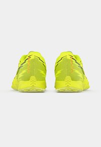 Neongule løbesko med åndbart mesh-overmateriale, tekstureret design og forstærket hæl. Har sorte detaljer og en fleksibel sål.