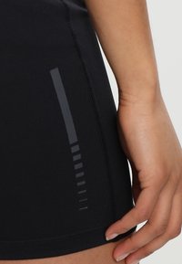 Černé sportovní šortky s hladkým povrchem, s bočním pruhem v tmavším odstínu a těsným střihem, který zvýrazňuje sportovní funkčnost.