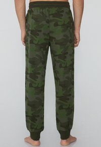 Camo-sweatpants in verschillende tinten groen, gemaakt van zachte stof, met een elastische tailleband en afgeknipte enkels.