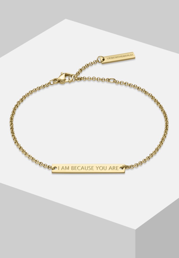 Bracelet en or avec un design en chaîne et une étiquette rectangulaire gravée portant la mention "JE SUIS PARCE QUE VOUS ÊTES". Fermoir avec une petite étiquette de marque.