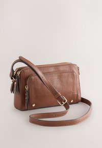 Sac bandoulière en cuir marron avec deux compartiments zippés, texture lisse, détails en métal doré et bandoulière ajustable.