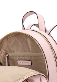 Sac à dos en cuir rose avec fermeture éclair dorée, doté d'un intérieur beige et d'une poche zippée à l'intérieur étiquetée "MICHAEL KORS".