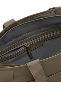 Binnenkant van een nylon tas in olijfgroen met een grijze voering, een ritssluitingvak en een leren label met de merknaam.