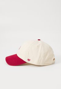Cappellino con un corpo in cotone beige e visiera rossa. Presenta ricami sulla parte anteriore e posteriore. Cinturino regolabile sul retro per la regolazione della taglia.