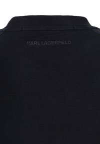 T-shirt nera in cotone con scollo a costine e logo "KARL LAGERFELD" in rilievo sul retro. Tessuto liscio con design aderente.