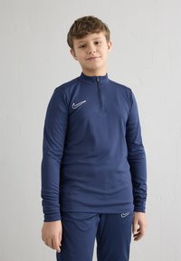 Marineblaues Sportoberteil mit Reißverschluss am Kragen aus glattem, dehnbarem Stoff, mit langen Ärmeln und einem weißen Nike-Logo auf der Brust.