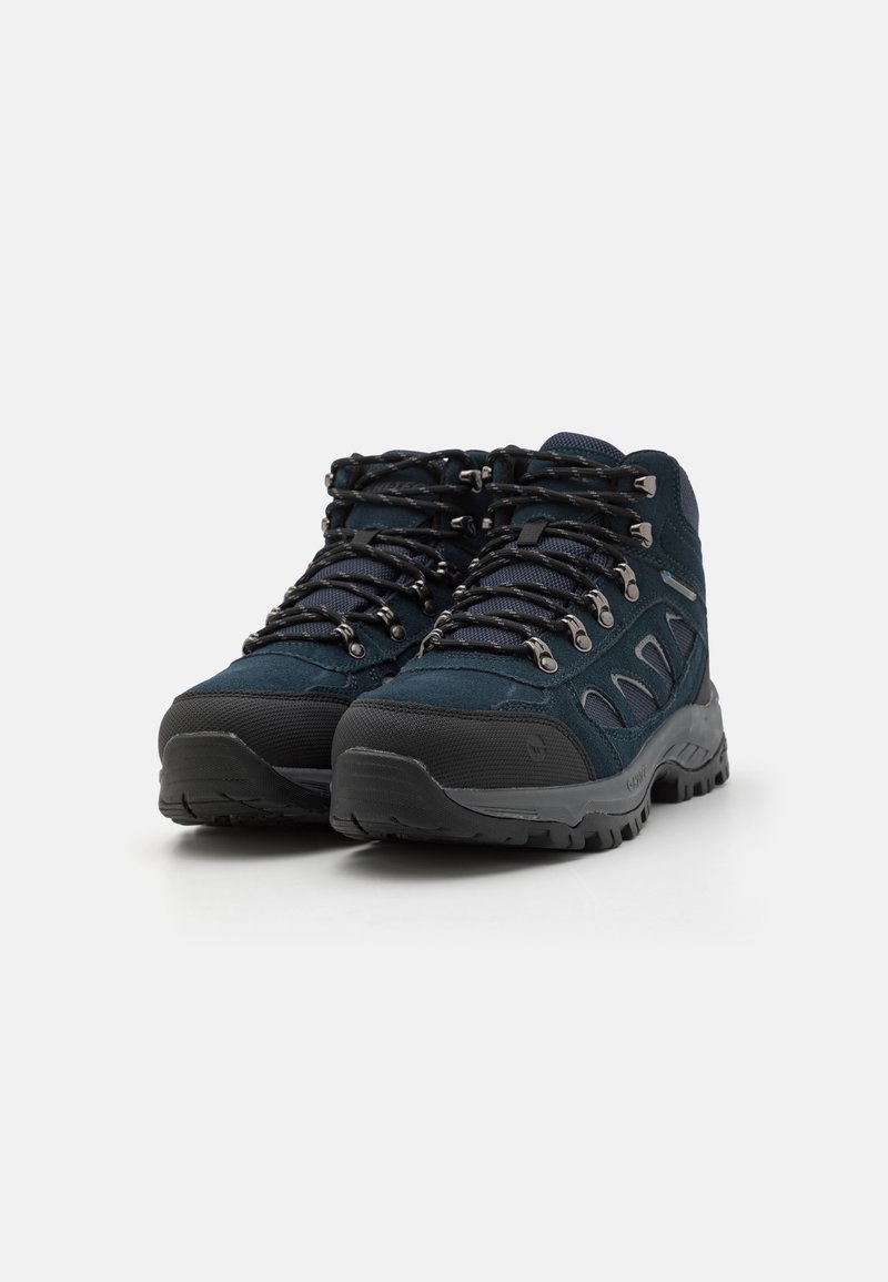 Botas de senderismo de color azul oscuro con parte superior de ante y sintético, suela de goma negra texturizada y ojetes metálicos. Presenta un collar acolchado y cordones.