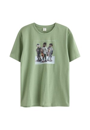 Grøn t-shirt med grafik af tre krokodiller, der står på skateboards iført urbant tøj og tilbehør.