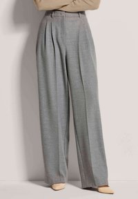 Helle graue, hochtaillierte Hose mit Falten, weitem Bein und strukturiertem Stoff, kombiniert mit spitzen beigen Absätzen.