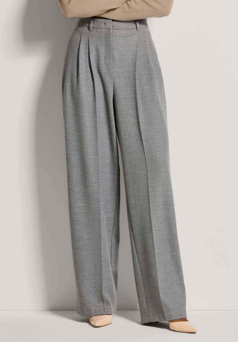 Helle graue, hochtaillierte Hose mit Falten, weitem Bein und strukturiertem Stoff, kombiniert mit spitzen beigen Absätzen.