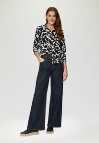 Wit en zwarte gestreepte shirt met lange mouwen, gecombineerd met wijde donkerdenim broek en zwarte schoenen met een dikke zool.