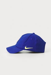 Casquette de baseball en coton bleu avec une visière incurvée et un logo Nike jaune. Comprend des œillets en tissu pour la ventilation et une sangle réglable à l'arrière.